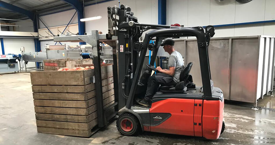 Medewerker rijdt in heftruck met pompoenoogst in magazijn