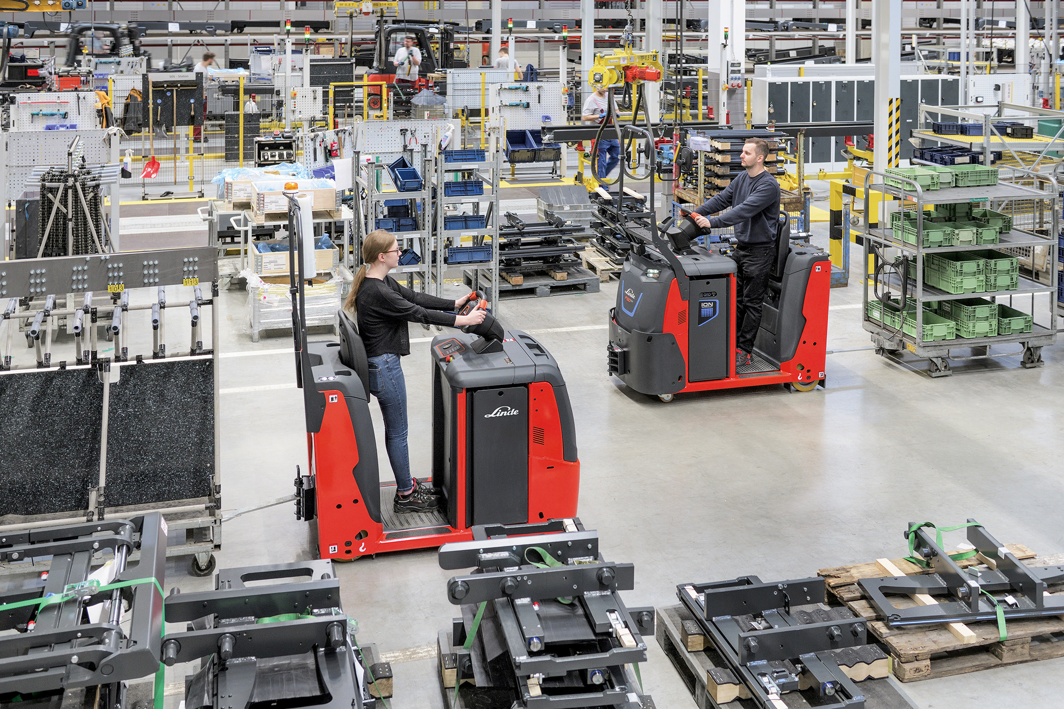 Twee medewerkers Linde in nieuwe elektrische Linde trekkers in magazijn - Efficiënt voor intern transport