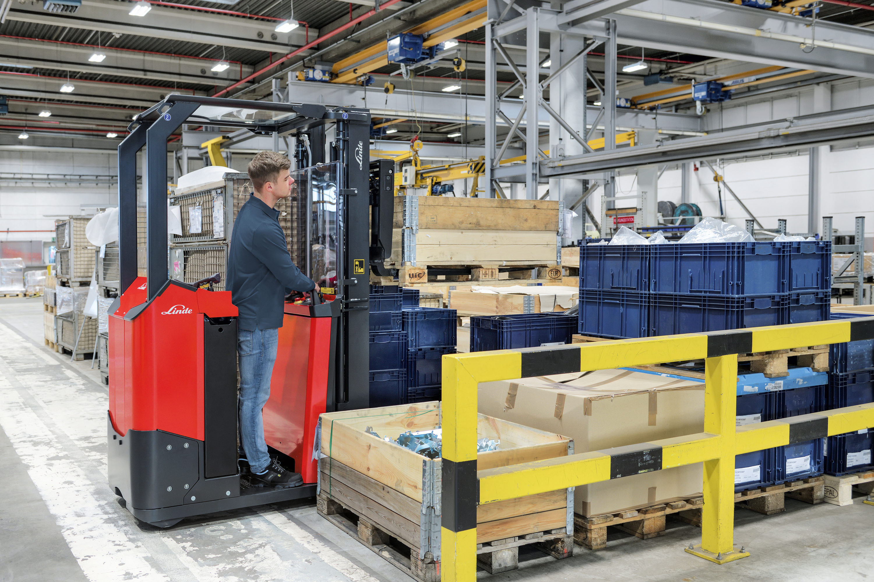 Compacte elektrische driewiel heftruck bestuurt door medewerker in magazijn - hefvermogen tot 1 ton